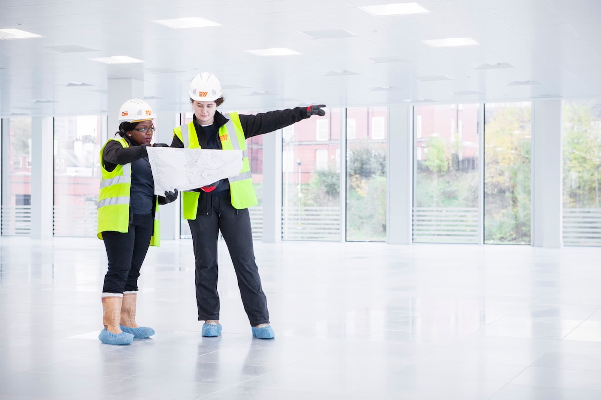 Two Eric Wright colleagues in hard hats and hi-vis walking through a bright, newly finished building